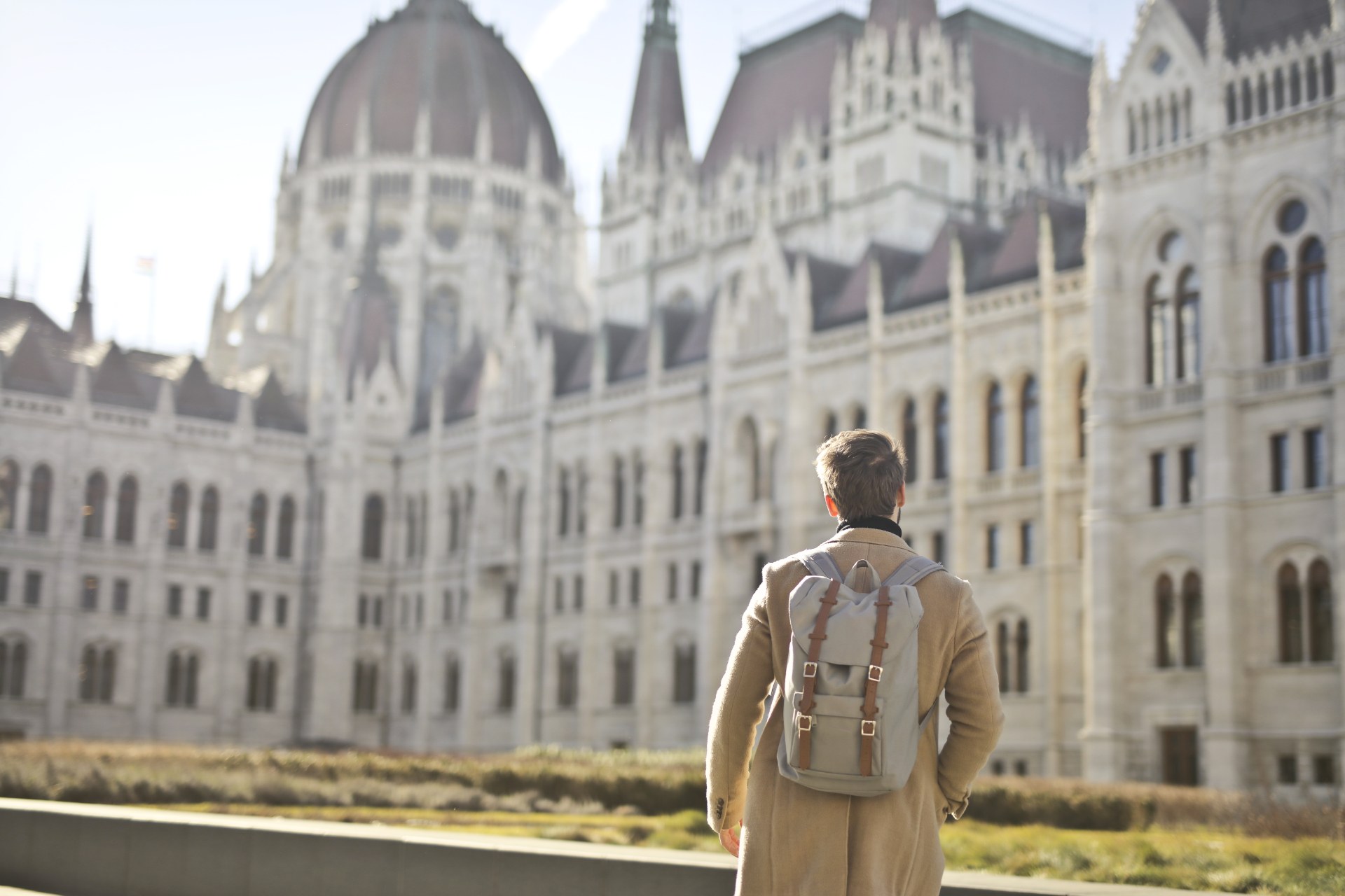 Junger Mann mit Rucksack vor dem ungarischen Parlamentsgebäude in Budapest