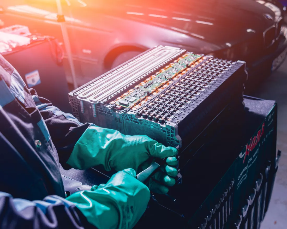 Haende in Handschuhen zerlegen das Batteriepaket eines Elektroautos